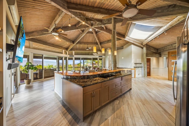 kitchen featuring wooden ceiling, dark stone counters, beamed ceiling, light hardwood / wood-style floors, and stainless steel refrigerator