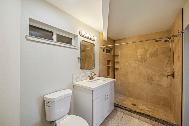 bathroom with toilet, a tile shower, vanity, and tile patterned floors