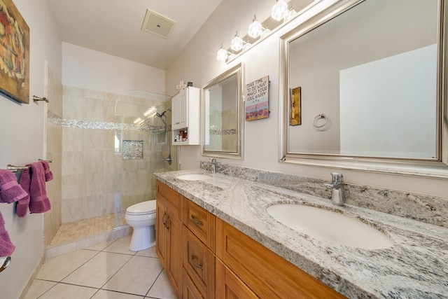 bathroom with toilet, a tile shower, vanity, and tile patterned floors