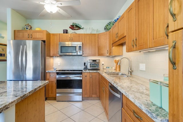 kitchen featuring sink, light tile patterned floors, light stone countertops, appliances with stainless steel finishes, and tasteful backsplash