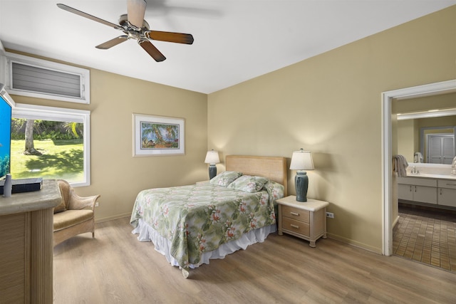 bedroom with light wood-type flooring, ensuite bathroom, and ceiling fan