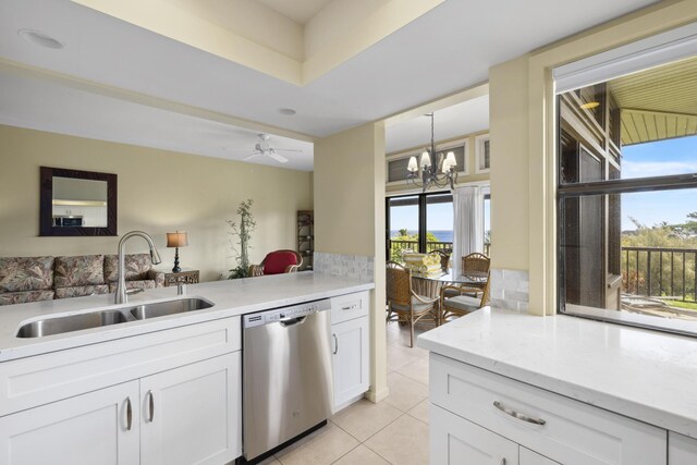 kitchen with pendant lighting, white cabinets, sink, light tile patterned flooring, and stainless steel dishwasher