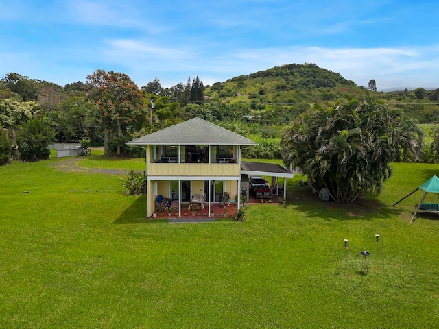 rear view of property featuring a yard, a mountain view, and a patio area