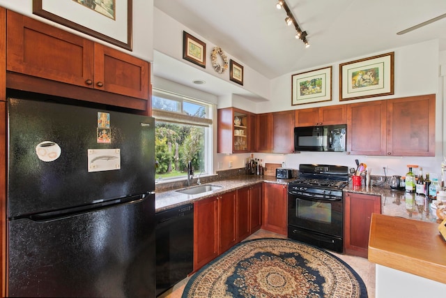 kitchen with dark stone countertops, track lighting, sink, and black appliances