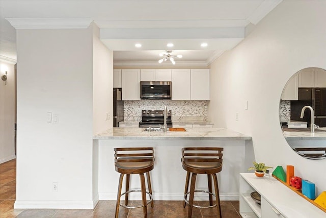 kitchen featuring backsplash, stainless steel appliances, tile flooring, sink, and a kitchen bar