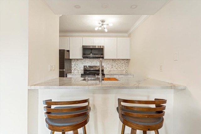 kitchen featuring backsplash, stainless steel appliances, a kitchen breakfast bar, and light stone countertops