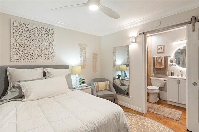 bedroom featuring crown molding, ensuite bath, a barn door, sink, and ceiling fan