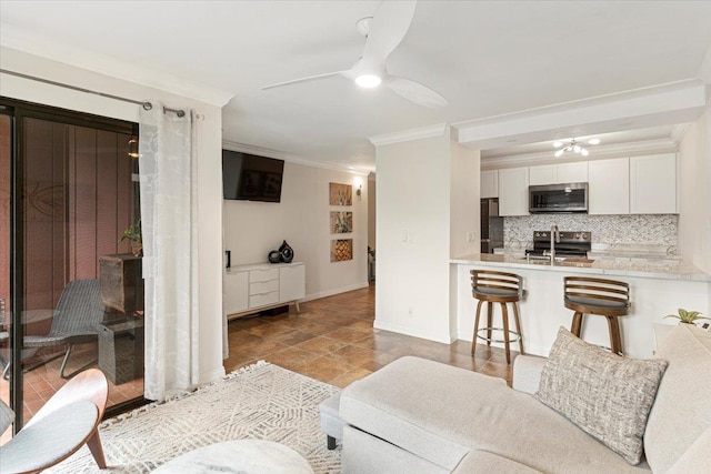 tiled living room with ornamental molding and ceiling fan