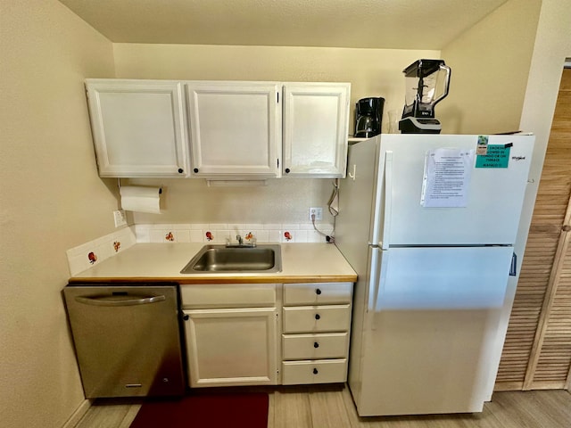 kitchen featuring dishwasher, white fridge, white cabinetry, and sink