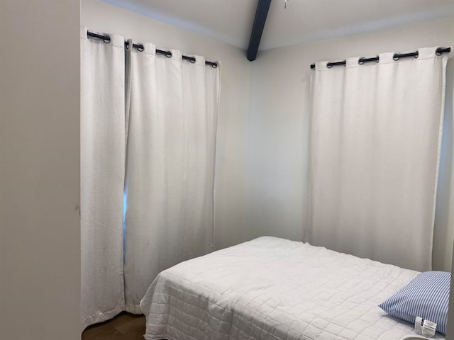 bedroom with hardwood / wood-style floors and beam ceiling