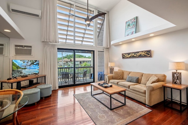 living room with a wall mounted air conditioner, a towering ceiling, and wood finished floors