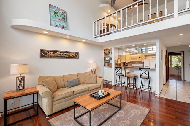 living area with a towering ceiling, recessed lighting, wood finished floors, and baseboards