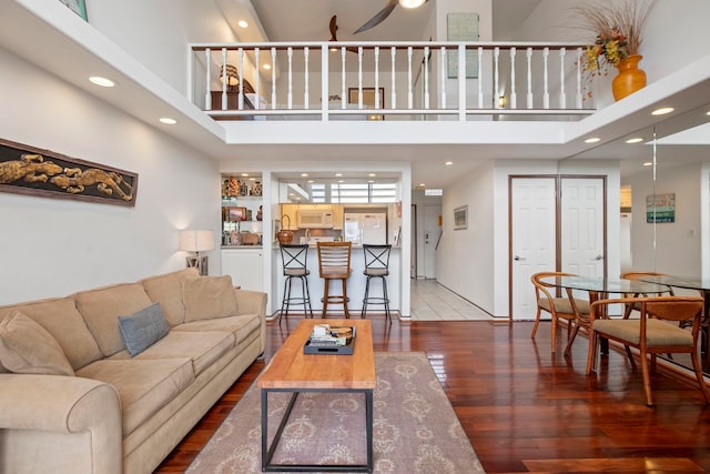living room featuring recessed lighting, wood finished floors, a ceiling fan, and a high ceiling