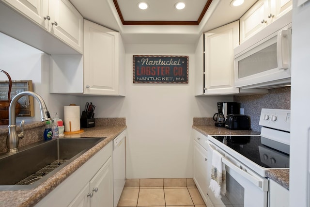 kitchen with white cabinetry, a sink, a raised ceiling, recessed lighting, and white appliances