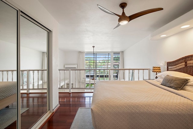 bedroom with expansive windows, ceiling fan, a closet, wood finished floors, and a wall mounted air conditioner