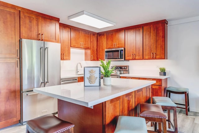 kitchen featuring light stone countertops, light hardwood / wood-style floors, sink, a breakfast bar, and stainless steel appliances