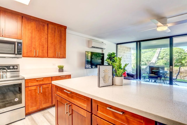 kitchen with light hardwood / wood-style flooring, ceiling fan, appliances with stainless steel finishes, light stone countertops, and a wall mounted air conditioner