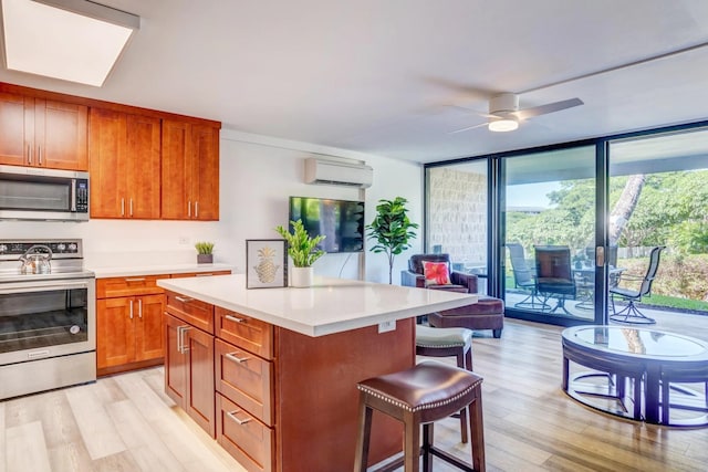 kitchen featuring appliances with stainless steel finishes, a kitchen island, light hardwood / wood-style floors, a wall unit AC, and expansive windows