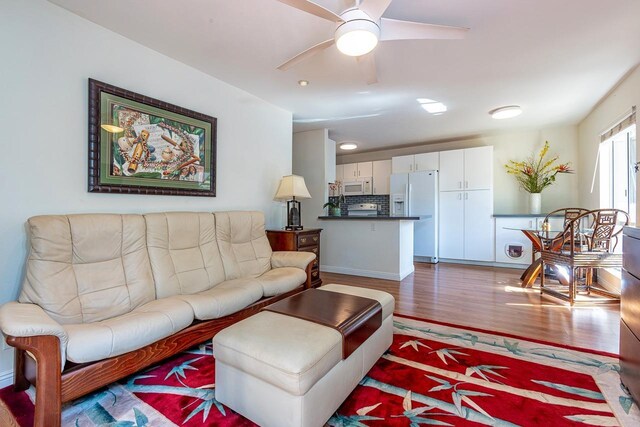 living room featuring ceiling fan and dark wood-type flooring