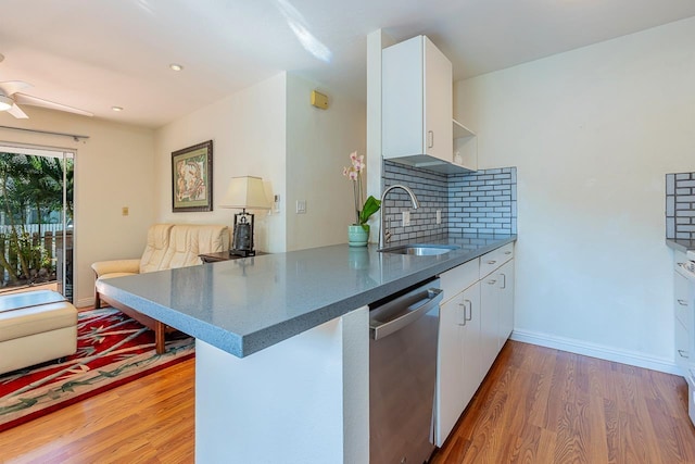 kitchen featuring dishwasher, kitchen peninsula, white cabinetry, and hardwood / wood-style flooring