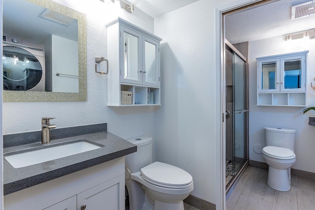 bathroom with hardwood / wood-style floors, vanity, toilet, an enclosed shower, and washer / clothes dryer