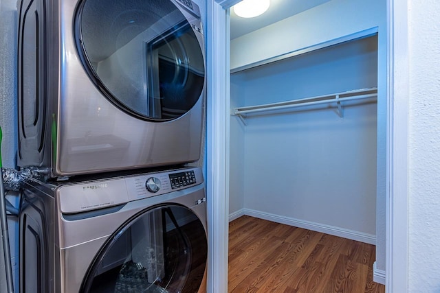 laundry room featuring stacked washer and dryer and dark wood-type flooring