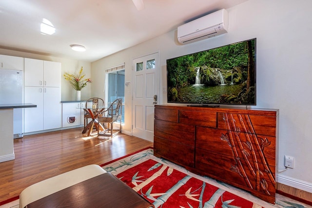 living room with an AC wall unit and light hardwood / wood-style flooring