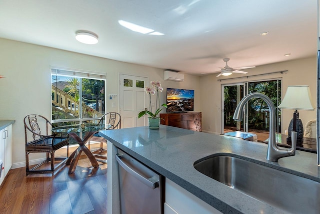 kitchen with a wall mounted AC, sink, stainless steel dishwasher, and plenty of natural light