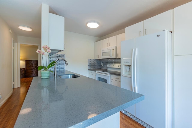 kitchen with white appliances, backsplash, white cabinets, sink, and wood-type flooring