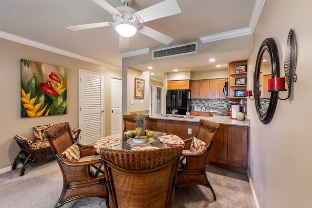 dining area with ceiling fan, light colored carpet, ornamental molding, and sink