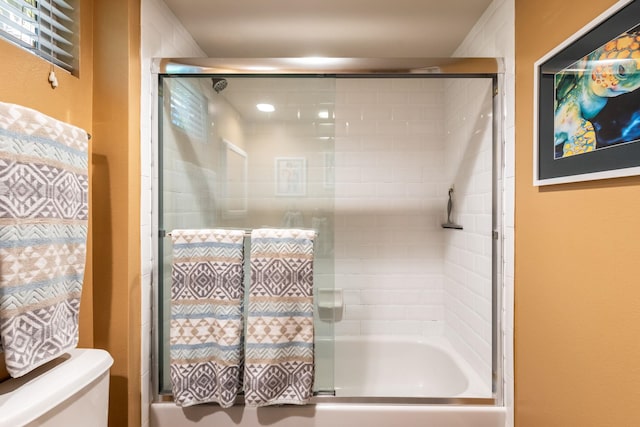 bathroom featuring enclosed tub / shower combo and toilet