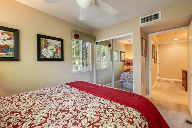carpeted bedroom featuring ornamental molding, a closet, and ceiling fan