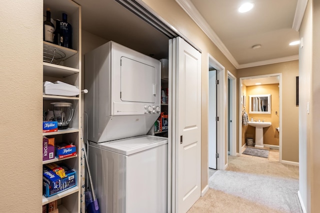 laundry area with light carpet, stacked washer and dryer, crown molding, and sink