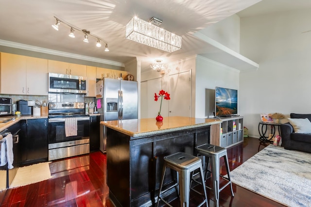 kitchen with tasteful backsplash, a center island, ornamental molding, appliances with stainless steel finishes, and dark hardwood / wood-style floors