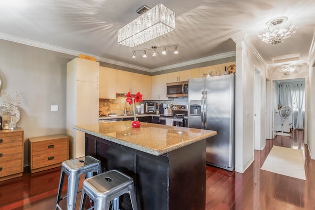 kitchen with dark wood-type flooring, stainless steel appliances, light stone countertops, a kitchen island, and a chandelier