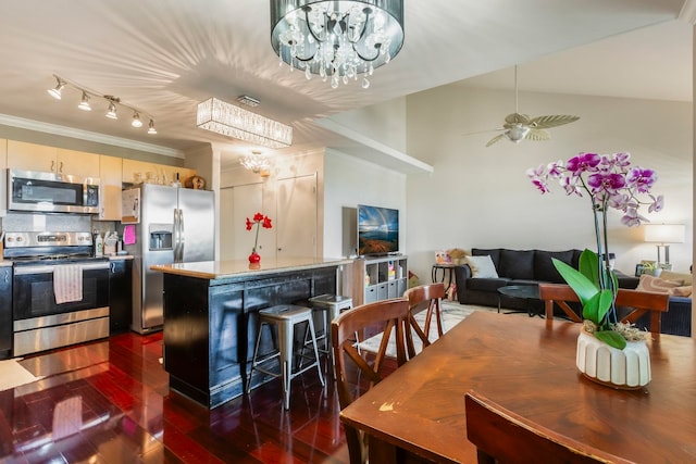 dining space with dark wood-type flooring, crown molding, and ceiling fan with notable chandelier