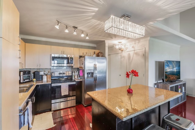 kitchen with light stone counters, ornamental molding, a center island, and appliances with stainless steel finishes