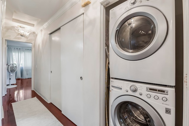 washroom featuring dark hardwood / wood-style flooring, stacked washer and dryer, and an inviting chandelier