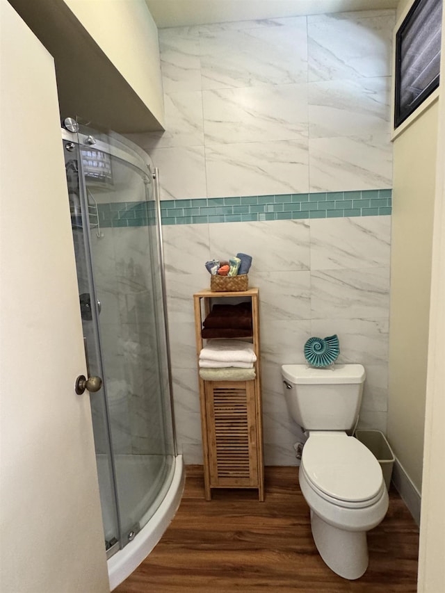 bathroom featuring toilet, a shower with shower door, and hardwood / wood-style floors