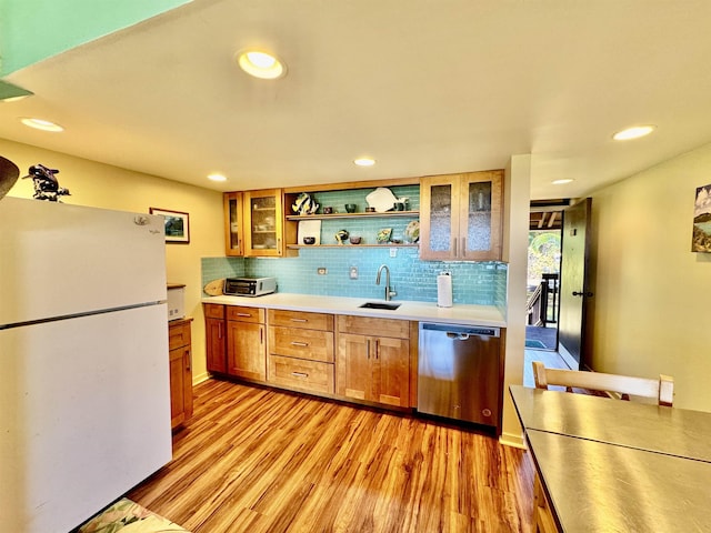 kitchen featuring sink, backsplash, white refrigerator, stainless steel dishwasher, and light wood-type flooring