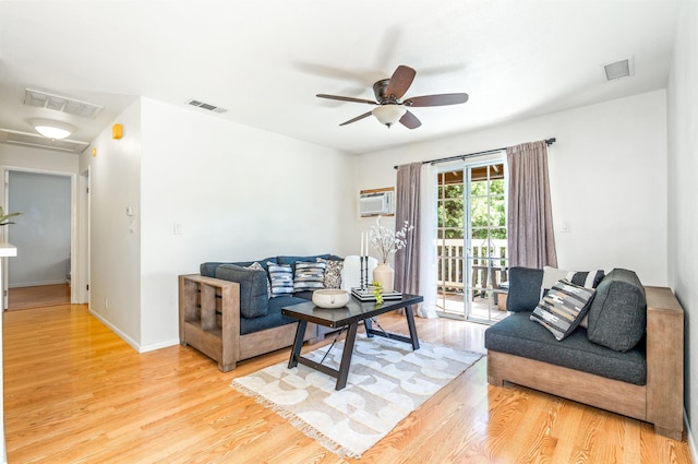 living room featuring ceiling fan, a wall mounted air conditioner, and light wood-type flooring