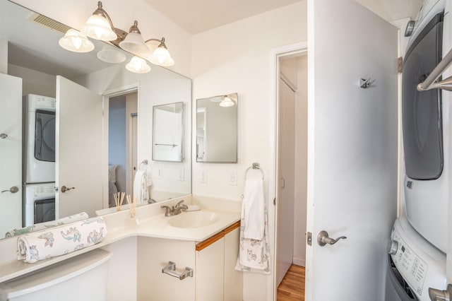 bathroom with hardwood / wood-style floors, a notable chandelier, vanity, and stacked washer and clothes dryer