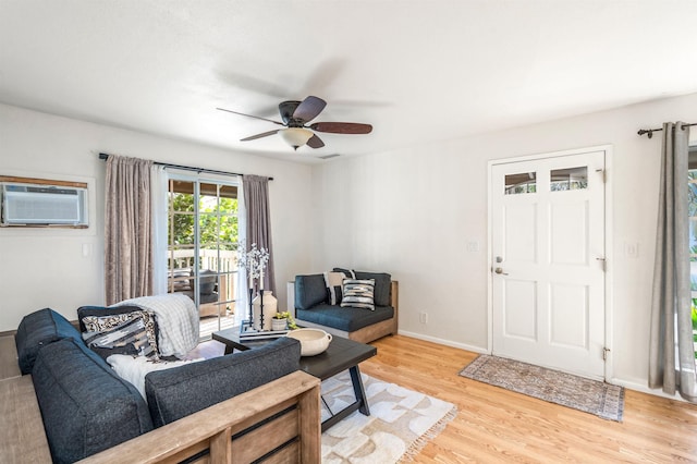 living room with light wood-type flooring, a wall unit AC, and ceiling fan