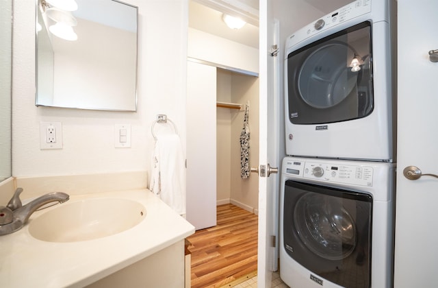 washroom featuring light wood-type flooring, stacked washer and clothes dryer, and sink