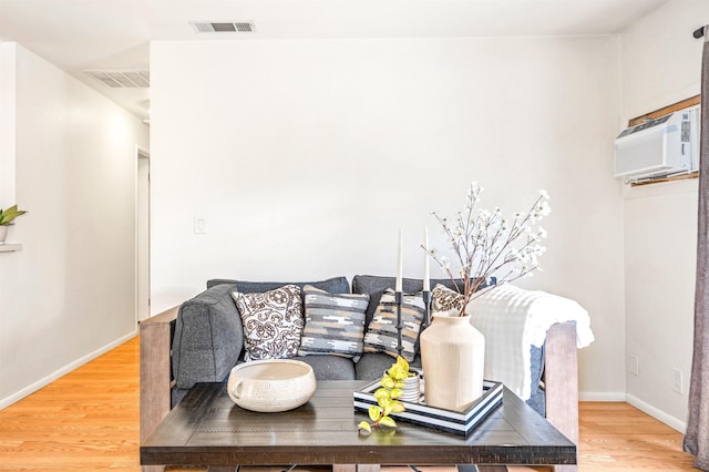 living room with a wall mounted AC and hardwood / wood-style floors