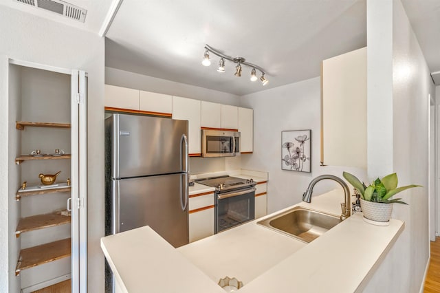 kitchen featuring sink, white cabinetry, stainless steel appliances, and light hardwood / wood-style flooring