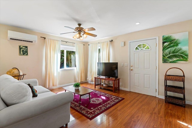 living room featuring wood-type flooring, ceiling fan, and a wall mounted AC