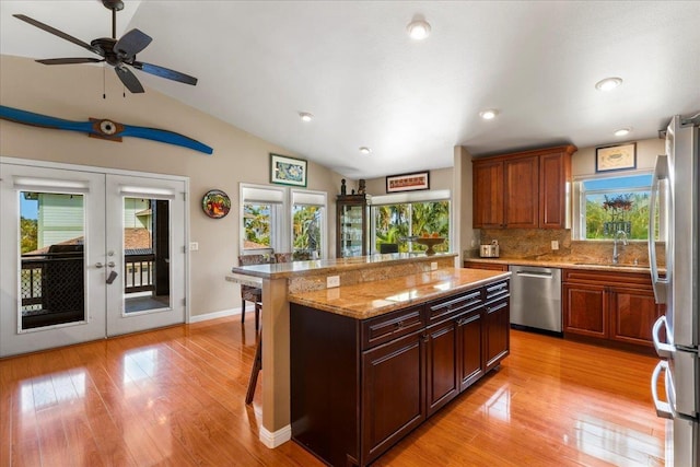 kitchen featuring appliances with stainless steel finishes, french doors, a kitchen bar, lofted ceiling, and backsplash