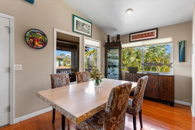 dining area featuring lofted ceiling, plenty of natural light, and light hardwood / wood-style flooring