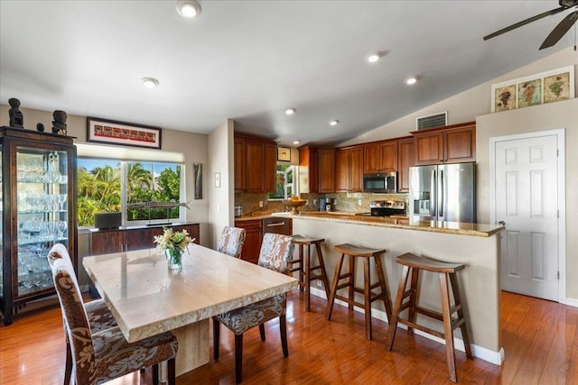 dining space featuring ceiling fan, lofted ceiling, and wood-type flooring